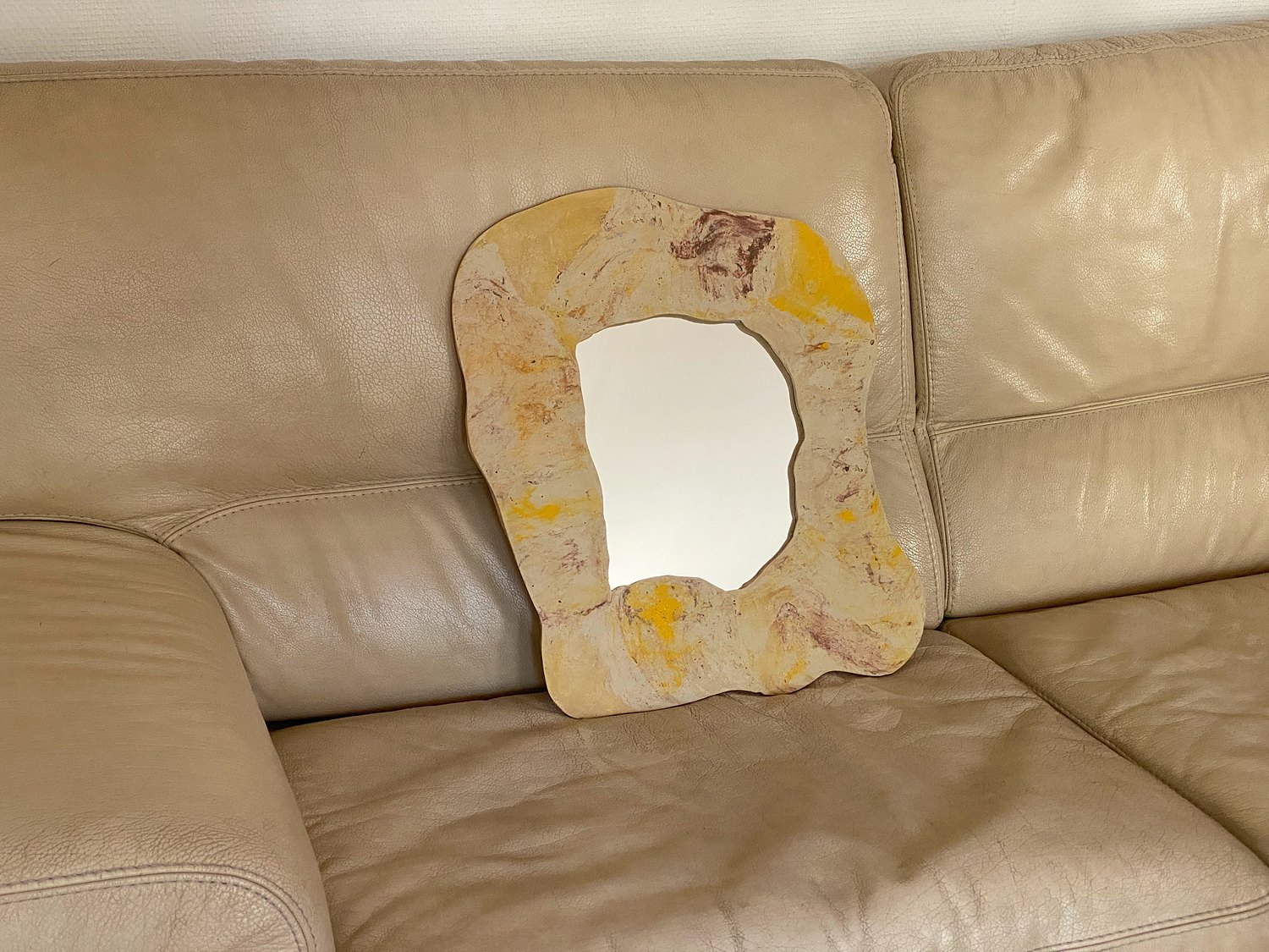 Miroir jaune et beige posé sur un canapé