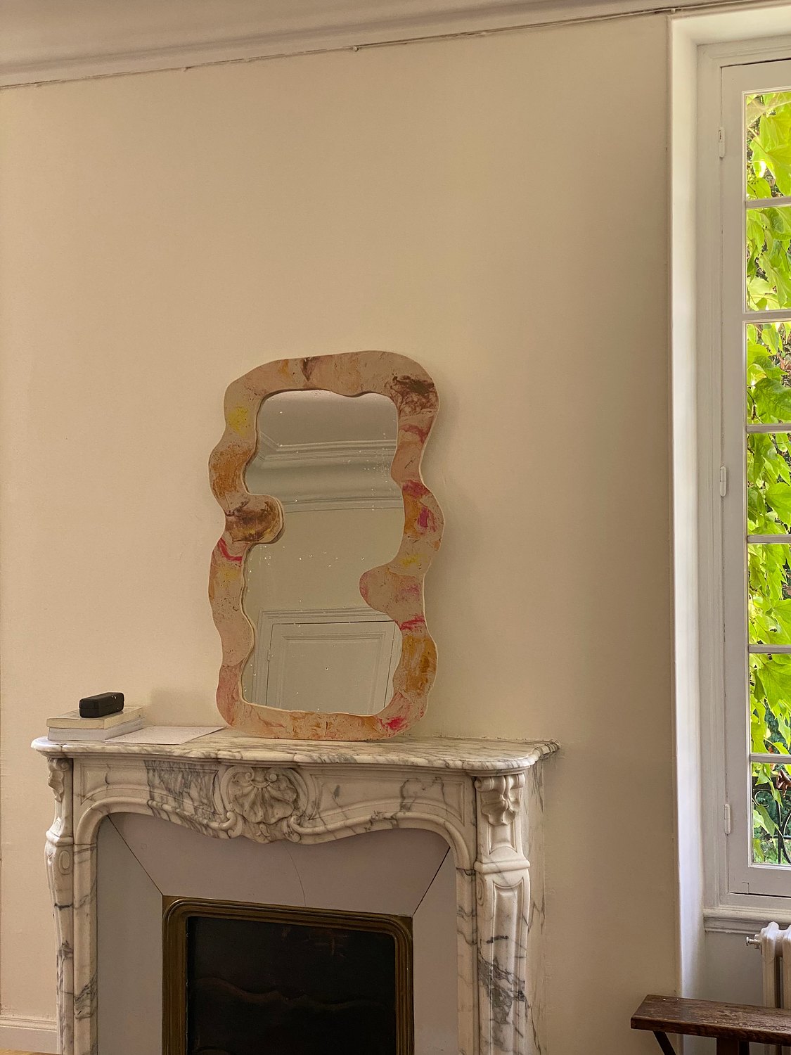 Miroir ondulé posé sur une cheminée en marbre
