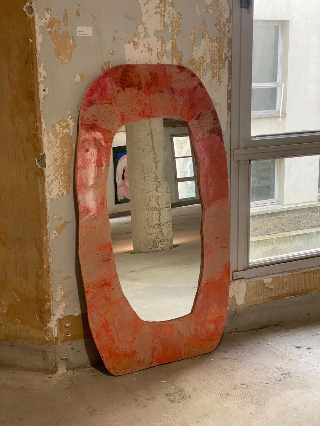 Grand miroir rouge posé contre un mur ancien