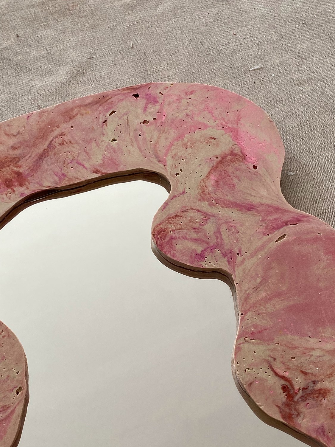 Détail d'un miroir rose aux contours ondulés