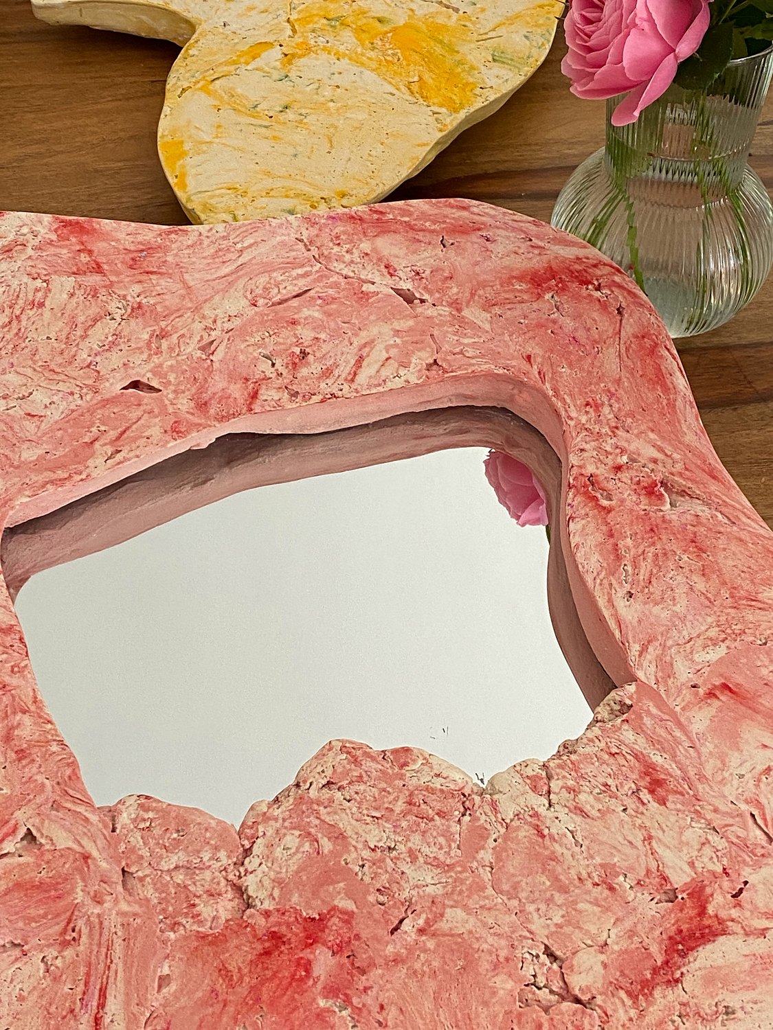 Détail d'un miroir rouge à côté d'un bouquet de roses