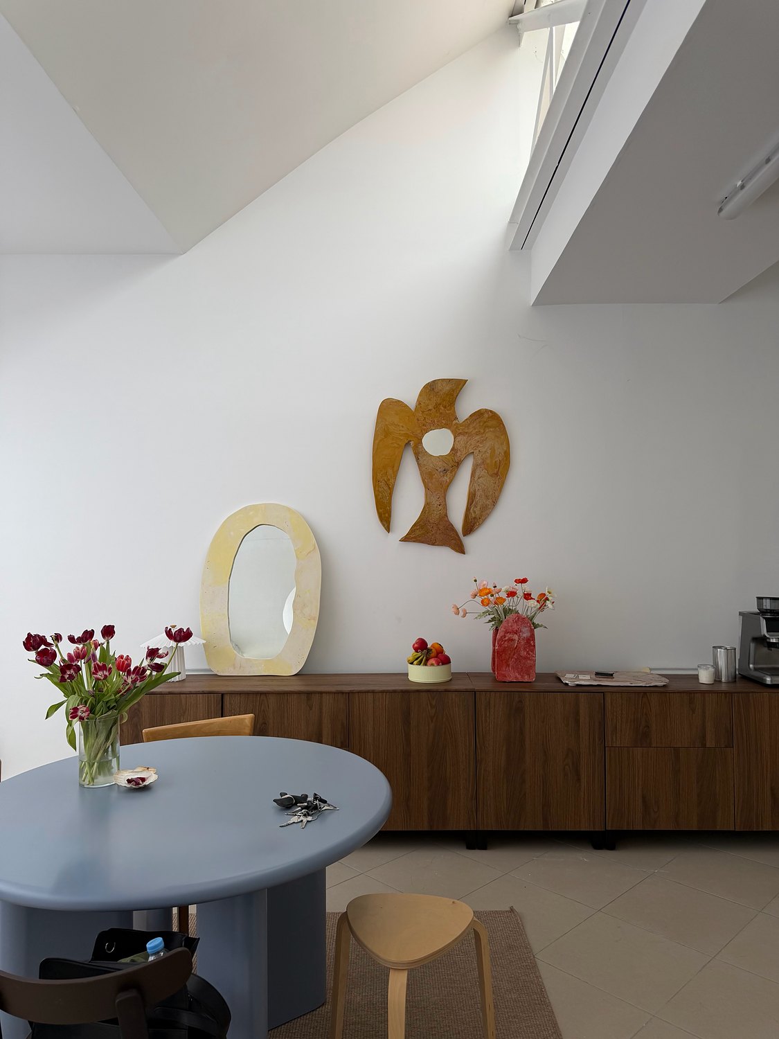 Miroir Oiseau miel au mur d'un salon, table ronde bleue et tulipes