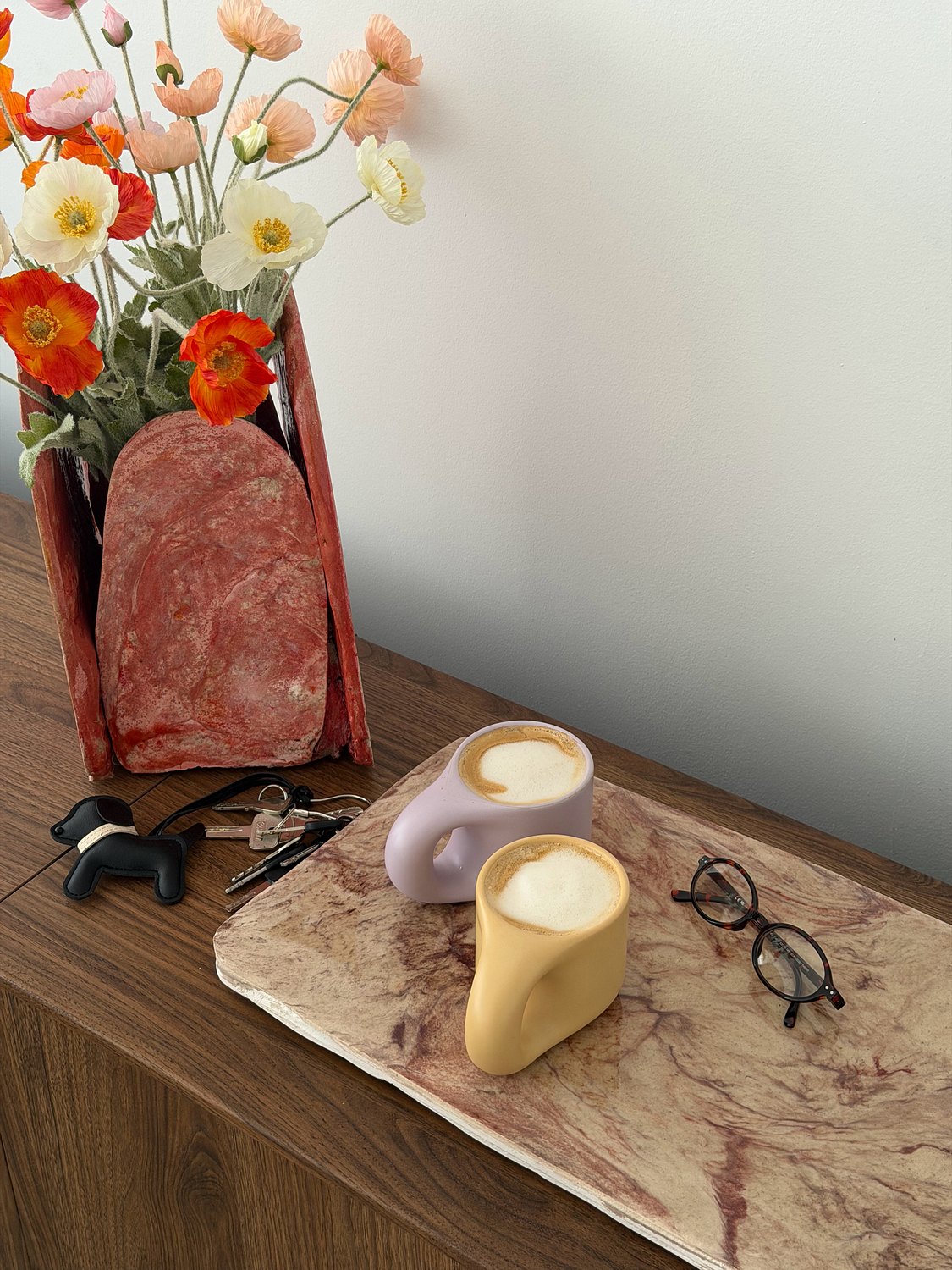 Vase rouge et fleurs sur un buffet, bougies sculptées